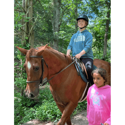 A girl and boy riding on the back of a horse.