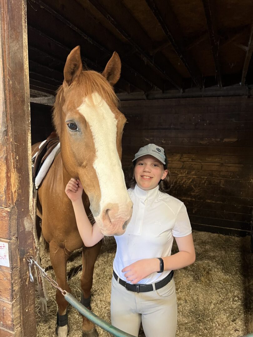 A woman standing next to a horse in a stable.