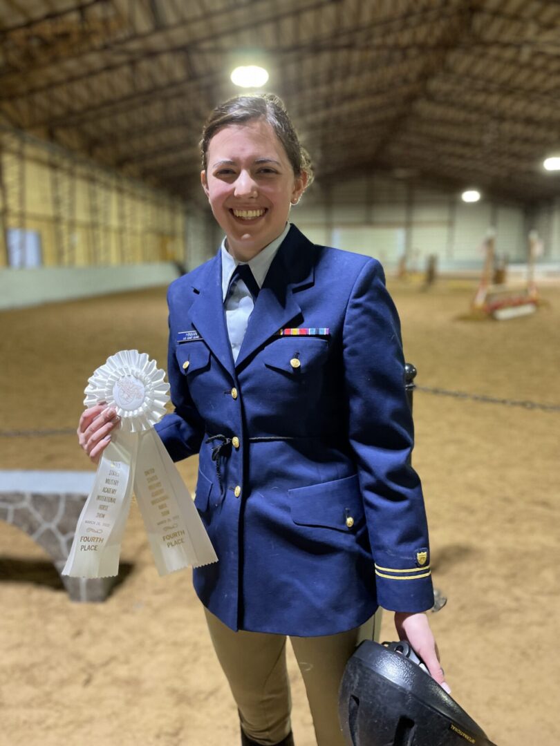 A woman in blue jacket holding a ribbon.