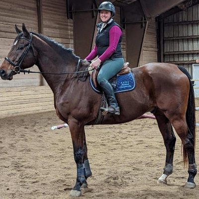 A woman riding on the back of a brown horse.