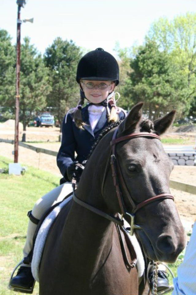 A girl in riding gear on top of a horse.