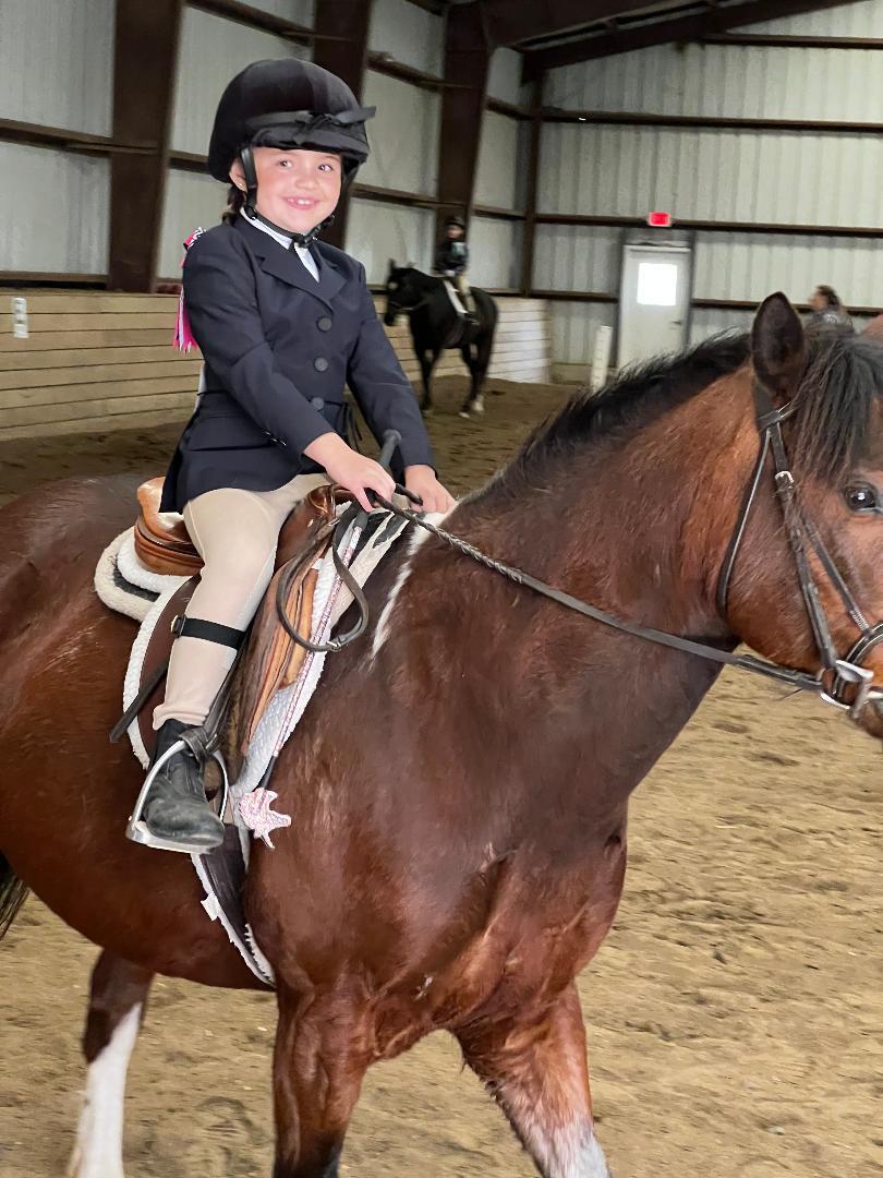 A young girl riding on the back of a horse.