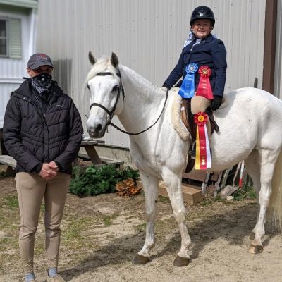 A person sitting on the back of a white horse.