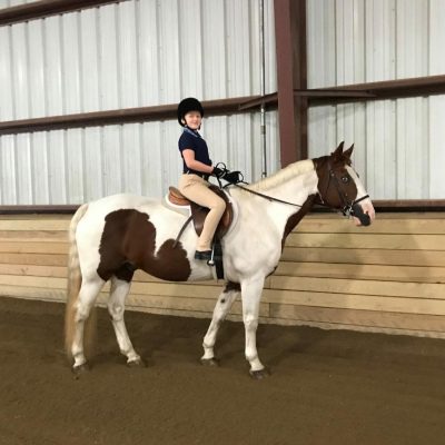 A girl is riding on the back of a horse.