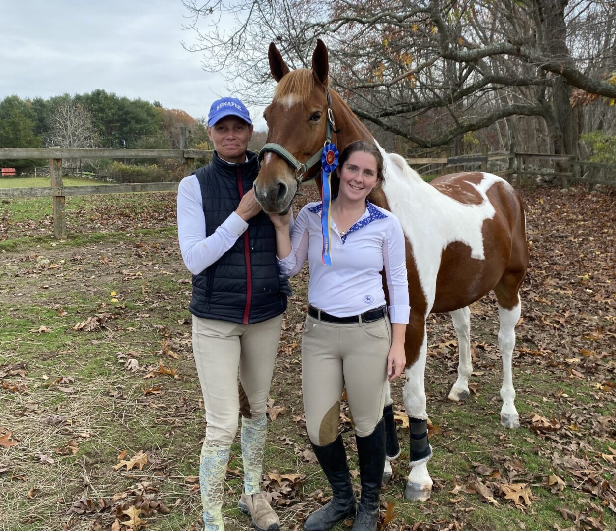 Two women standing next to a horse in the woods.